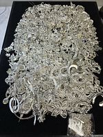 Overall pile of silver-tone jewelry spread on black surface