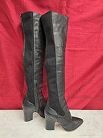 Side view of both boots showing leather front, knit back panel, block heels, inner zipper