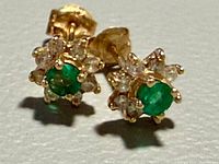 Front view of both earrings showing green center stones and clear accent stones in yellow gold setting