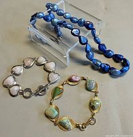Group shot of blue pearl necklace, heart bracelet, gemstone bracelet