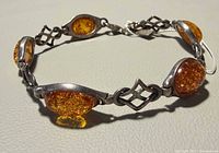 Full view of sterling silver bracelet showing five amber cabochons and connectors