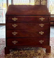 Front view of closed secretaire showing four drawers and brass hardware