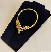 Full view of gold plated floral choker on display board