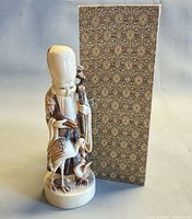 Fukurokuju figurine standing beside patterned box