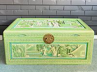 Front view of carved green wooden chest with brass clasp