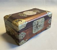 Three-quarter view of wooden jewelry box showing brass corner mounts and hinge clasp