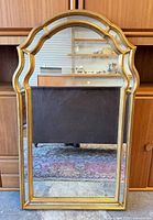 Front view of the arched gold-tone framed mirror