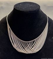 Front view of cascading multi strand silver bib necklace on display bust