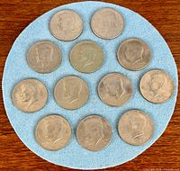 Overhead view of 12 Kennedy half dollars arranged on blue felt