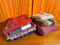 Stack of eight folded scarves on wood surface