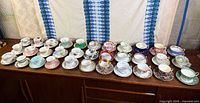 Full lot of teacup and saucer sets lined on sideboard
