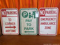 Three metal parking signs standing side by side