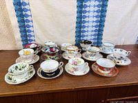 All fifteen tea cup and saucer sets displayed on cabinet
