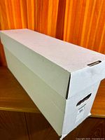 Closed white cardboard long comic box on shelf