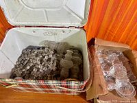 Open plaid cooler showing large quantity of loose chandelier crystals and adjacent box of glass bobeche