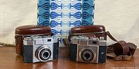 Both Zeiss Ikon Contina cameras with leather cases on table