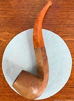 Full view of briar pipe with curved amber stem on blue circle