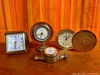 Group shot of all four clocks on wooden surface with fabric backdrop