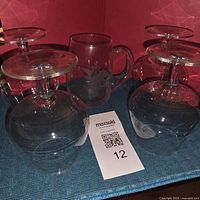 Five glasses shown, four stemmed snifters upside down beside mug
