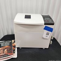 Front view of Panasonic Bread Bakery machine with cookbook beside