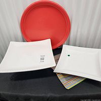 Group view of red round platter, two white ceramic platters, striped glass platter