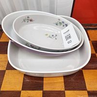 Three nested casserole dishes, two oval floral and one square white