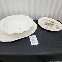 Large white turkey platter underneath scalloped bowl beside floral platter