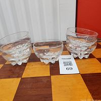 Three of the clear glass dessert bowls on chessboard surface