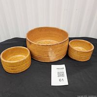 Three matching brown ceramic bowls displayed