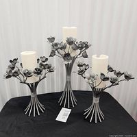 Front view of all three metal floral candle holders with candles