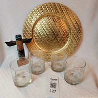 Front view of all items: four glasses, gold tray, wood totem