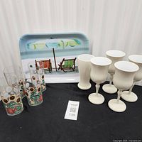 Full lot view showing five ivory goblets, four sunflower tumblers, beach scene tray