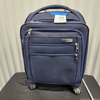 Front view of Samsonite navy carry-on with compartments and wheels visible