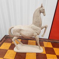 Full view of speckled resin horse sculpture on base