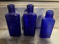 Three cobalt blue rectangular bottles standing upright