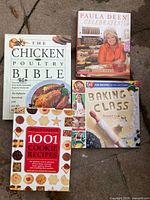 Top-down view of the four cookbooks: Paula Deen Celebrates!, The Chicken & Poultry Bible, Baking Class, 1001 Cookie Recipes
