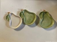 Front view of three pear-shaped plates showing glaze colors and leaf detail
