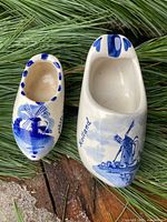Two Delft blue ceramic clog shoes on greenery background