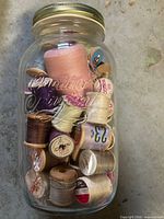 Front view of filled glass jar showing mix of thread spools