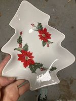 Top view of white ceramic Christmas tree-shaped dish with poinsettia and holly design