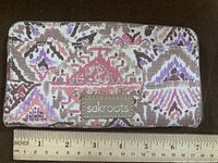 Front view of Sakroots wallet showing pattern, logo patch, ruler for scale