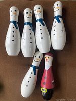 Six holiday‐themed wooden bowling pins on brown surface