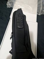 Side view showing built-in 3-digit combination lock and zipper detail of black sling bag