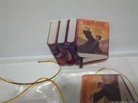 Three Harry Potter book-shaped ornaments with gold cords, one showing Sorcerer’s Stone cover