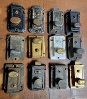 Front view of all 12 cast iron door latches on wooden surface