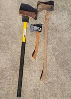 Three axes laid out on concrete showing overall length and handles