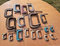Overview of all 18 assorted C-clamps laid out on tabletop