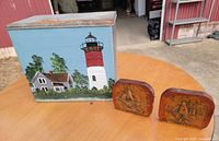 Front of painted metal milk box with lighthouse scene, bookends alongside