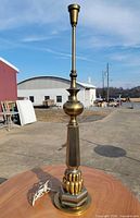 Full view of tall brass lamp base on table outdoors