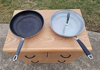Top view of both frying pans showing interiors and lid on right pan